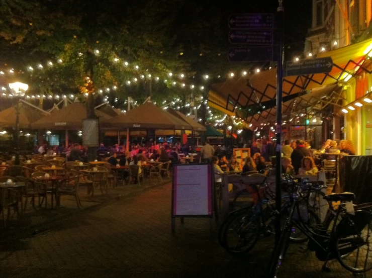 people are eating and drinking outside in a restaurant at night