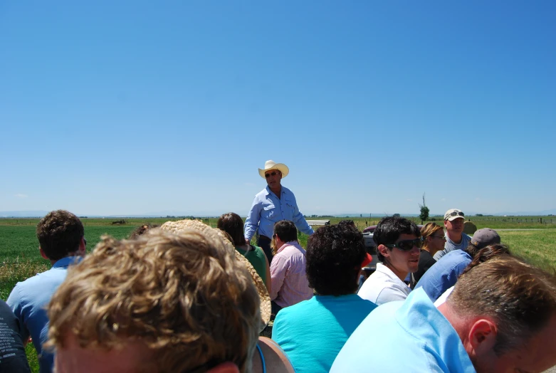 a man in a white shirt and hat is speaking to a group of people