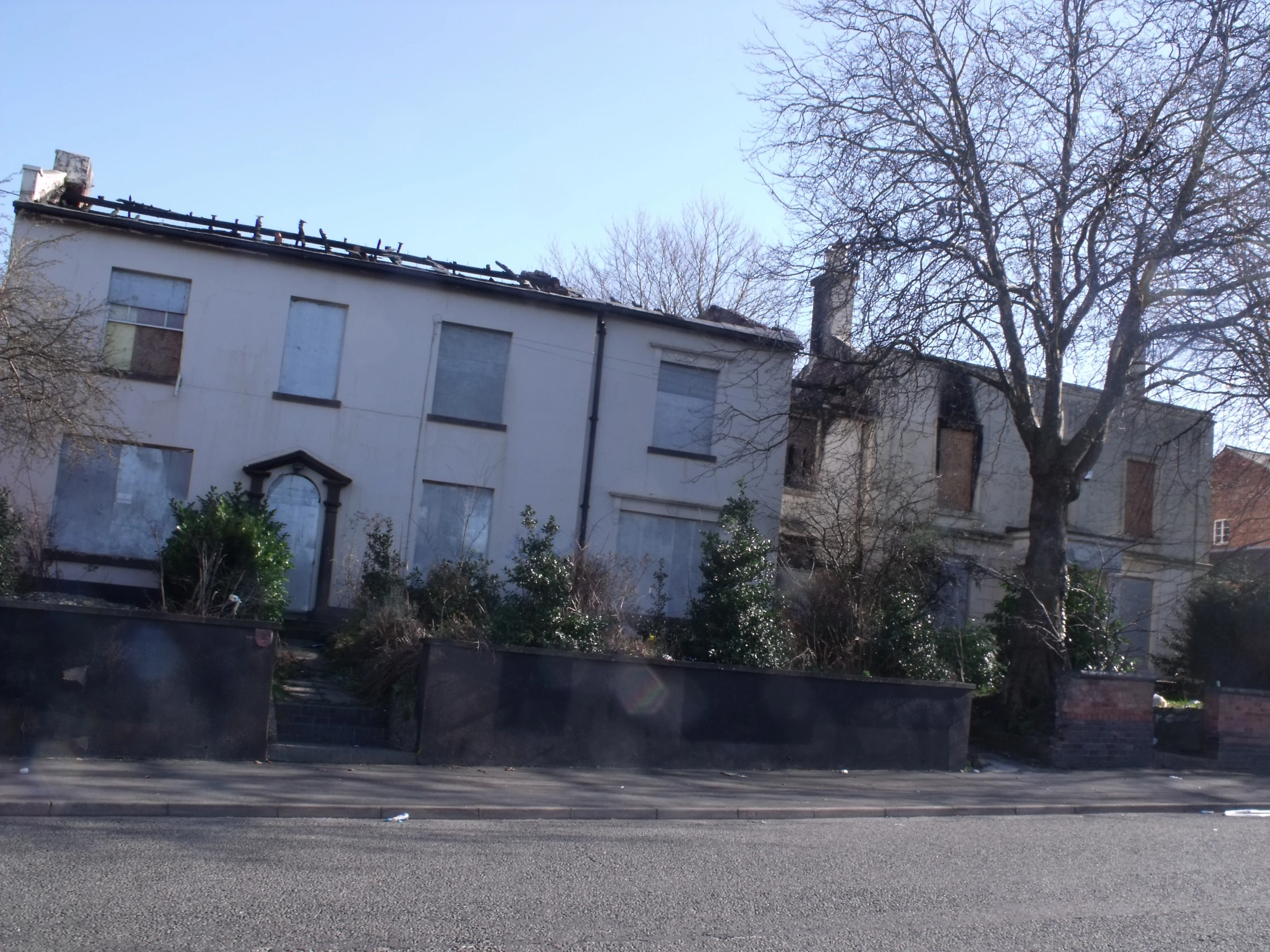 the house with a large lot of windows has a fence by it