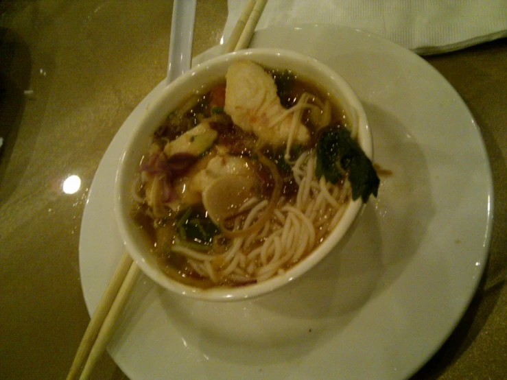 bowl of asian noodles, vegetables, and sauce on a plate