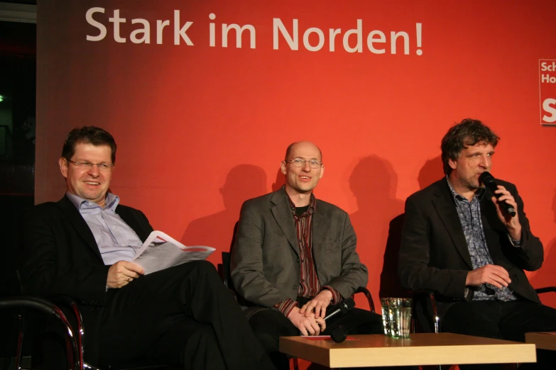 three men are sitting on a stage next to each other