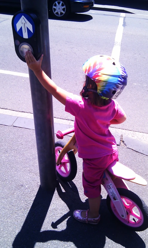 a small girl riding a bicycle next to a street sign
