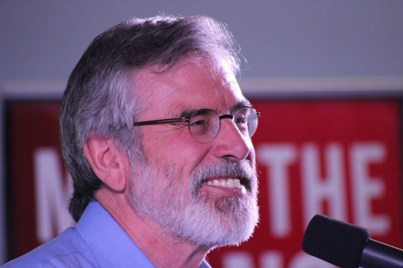 a smiling older man is holding a microphone