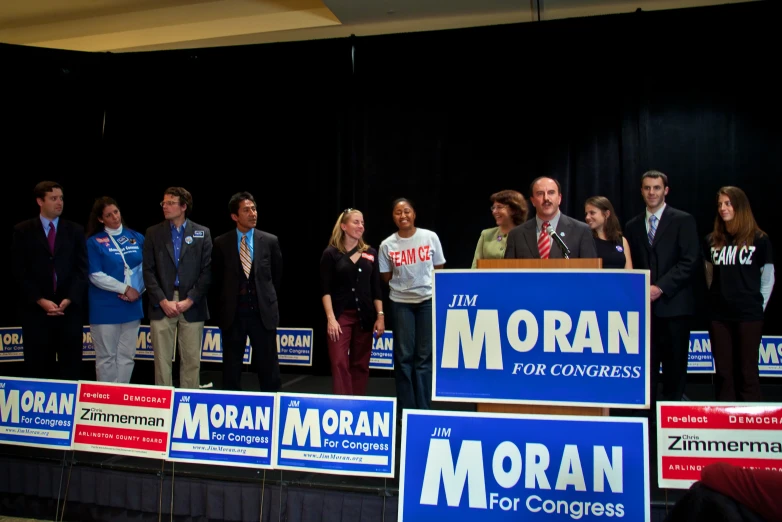 people standing on stage with political signs in front of them