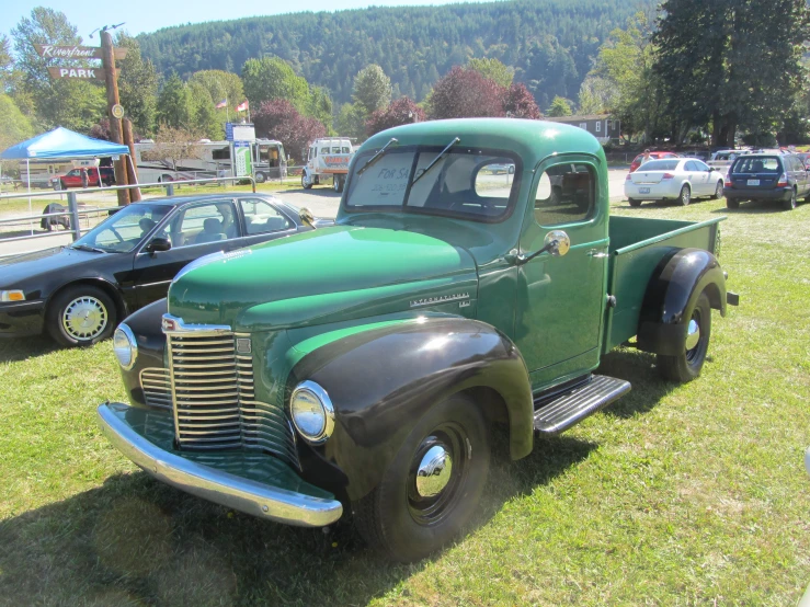 an old green truck is parked on some grass