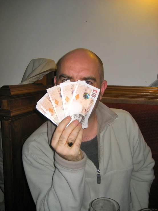 a man covering his face with five thousand notes