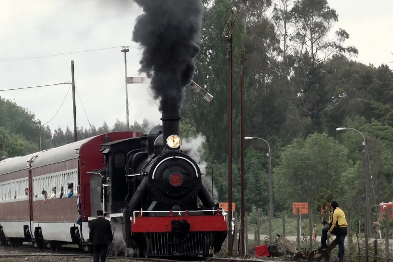 a locomotive with black smoke is moving down the tracks