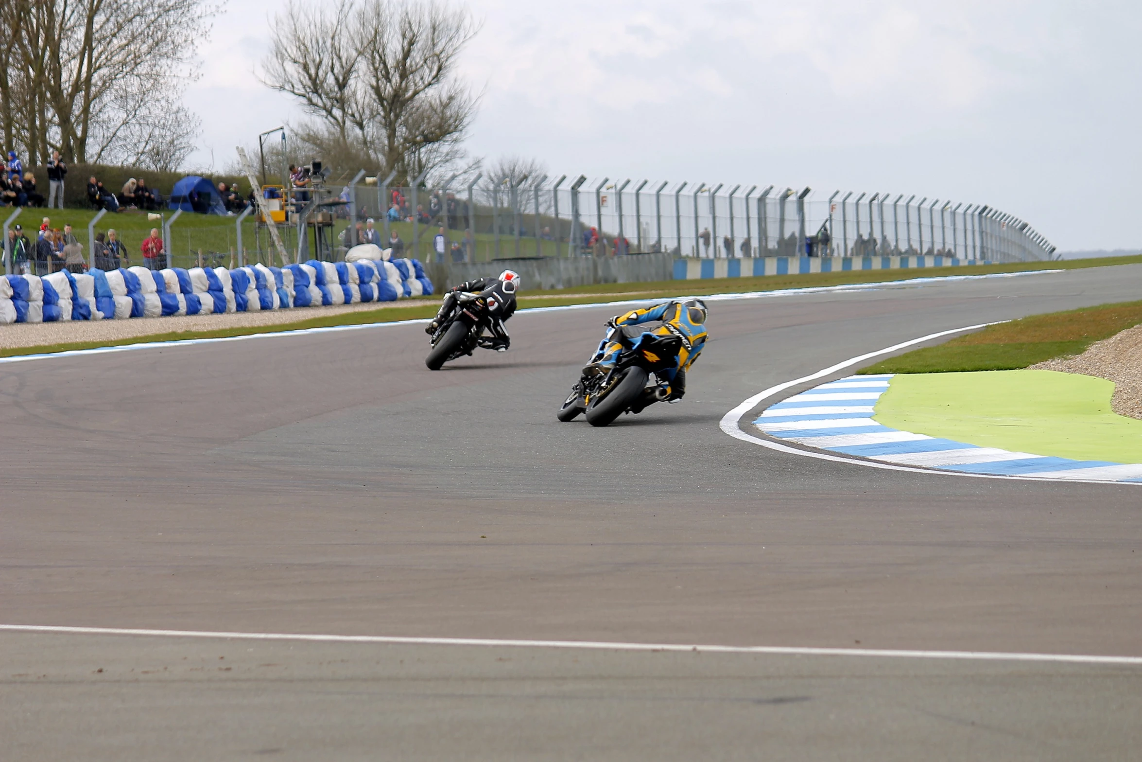 two motorcycles racing on a track with spectators