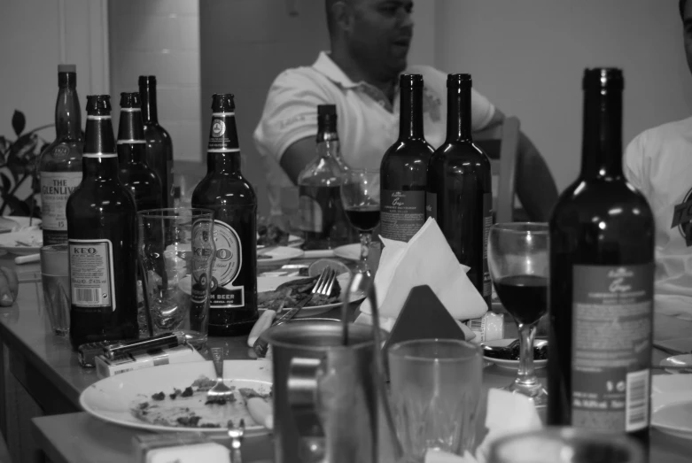 a group of men sitting at a table with bottles of wine in front of them