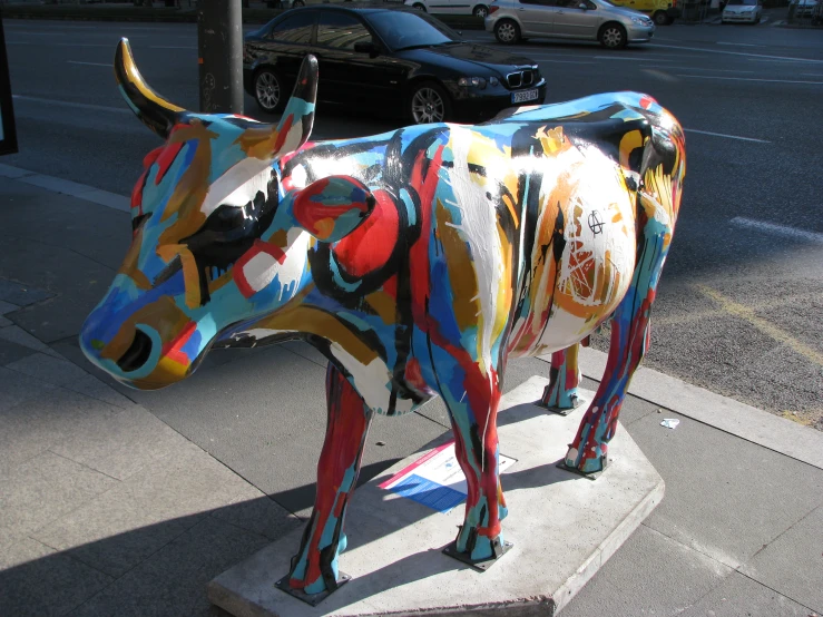 colorful cow statue on the side walk on a city street