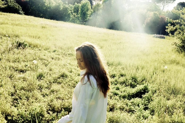 a girl in white shirt walking in field of grass