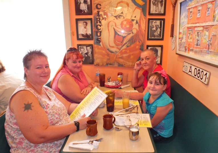 two woman, one boy, two girls and an adult sitting at a table