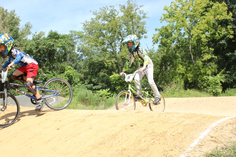 two people on bicycles riding down a dirt road