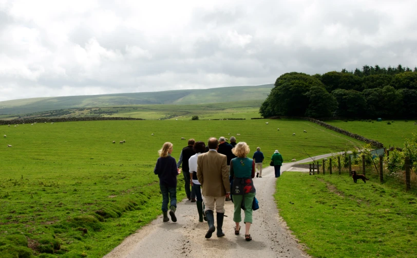 some people walking down the road towards the fields