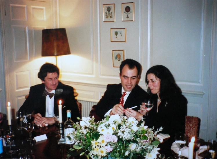 four people dressed in business suits sit together at a dinner table