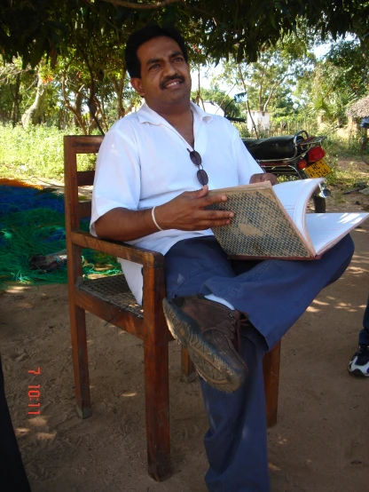 a man in a white shirt and blue jeans reading a book