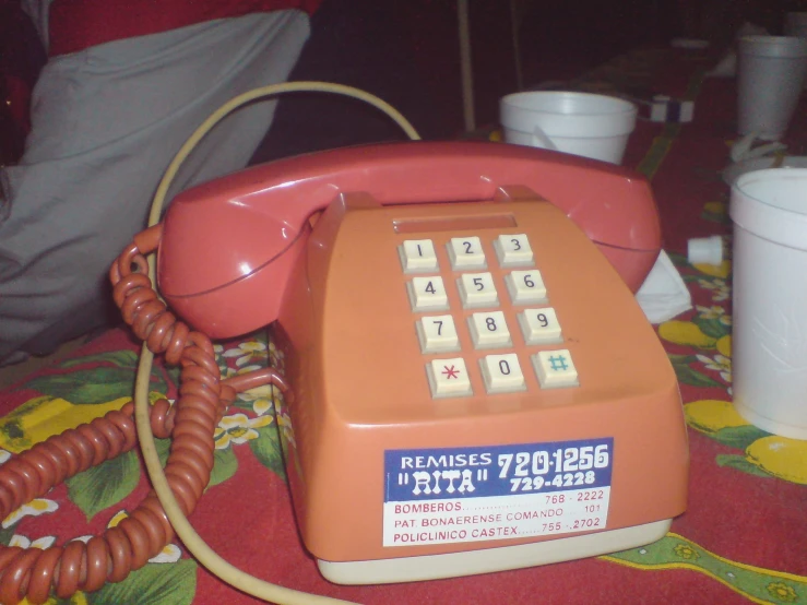 an orange and white telephone with numbers attached to it