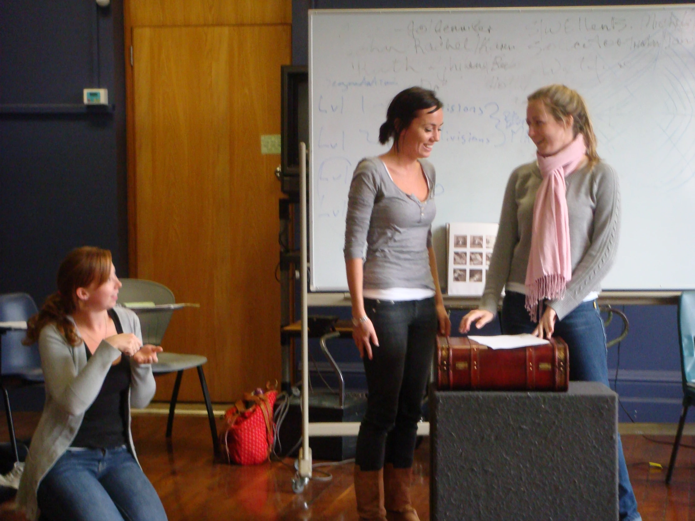 two girls speaking to each other in front of a chalk board