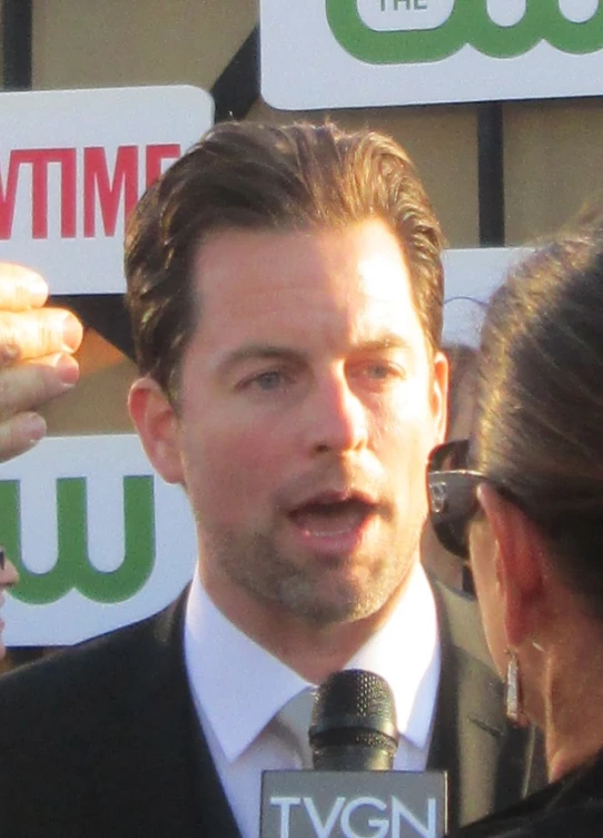 man in suit and tie making a speech to a tv reporter