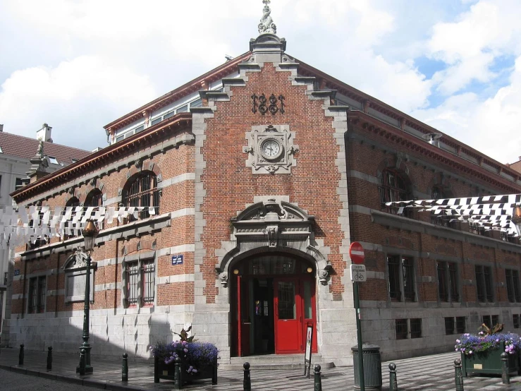 a red door on a tall brick building with a checkered banner on it