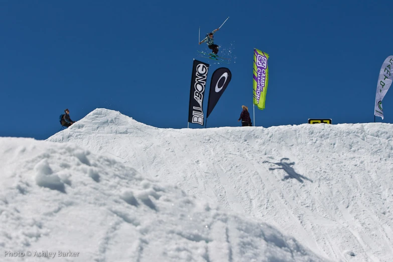 a snowboarder flies off the side of a snow ramp