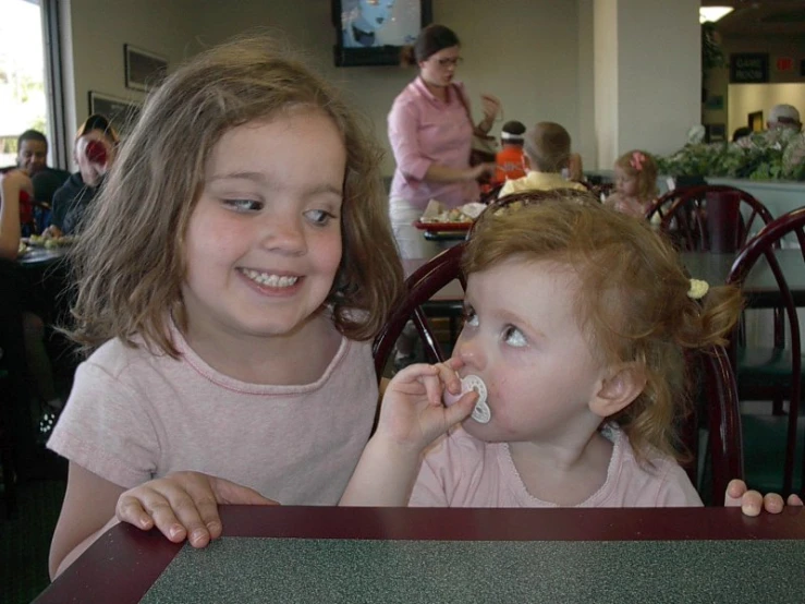 two girls sitting at a table eating donuts