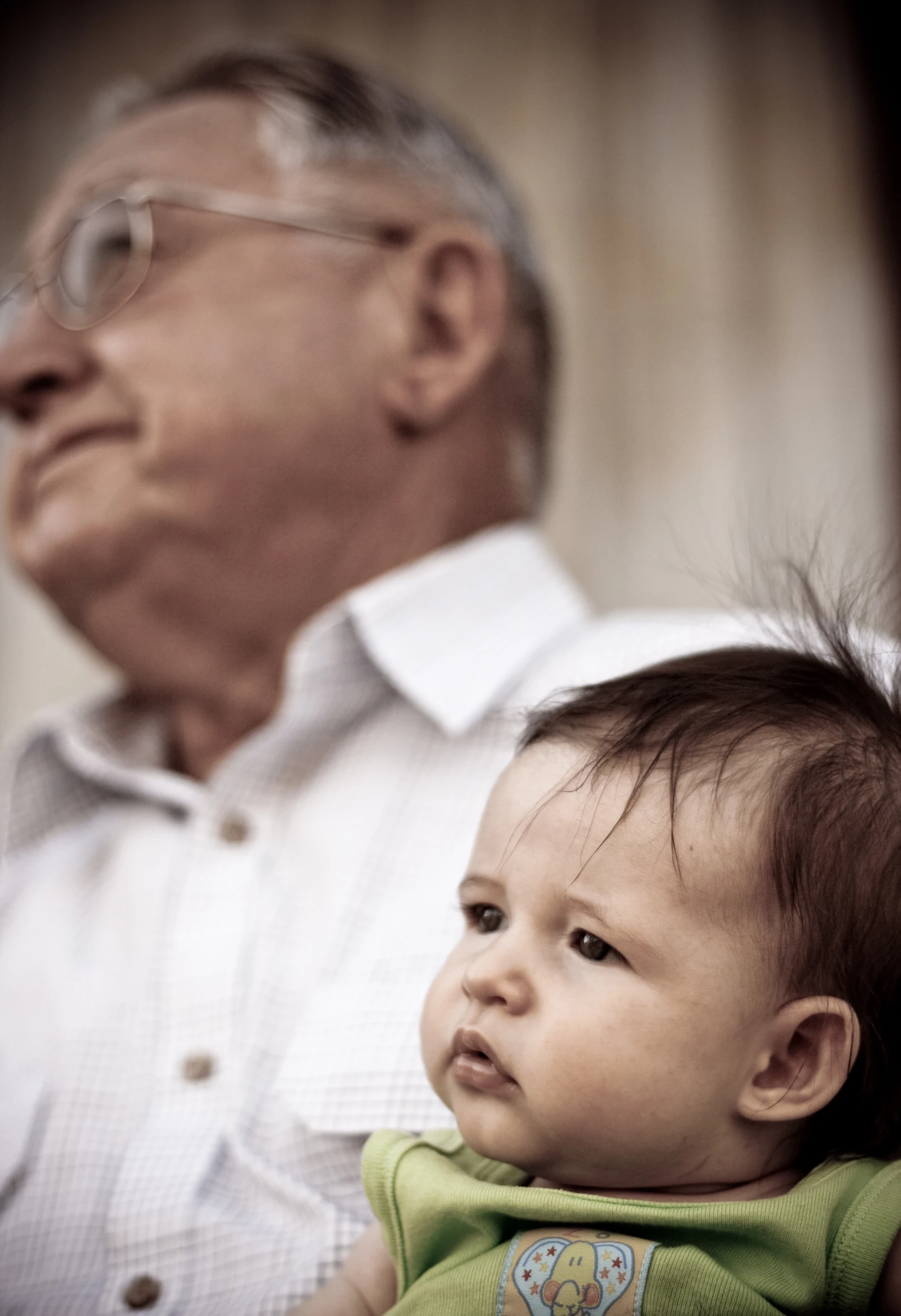 an elderly man holding his infant in the arms