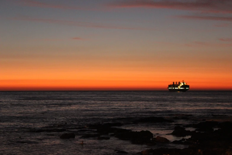 a large ship sailing in the ocean at sunset