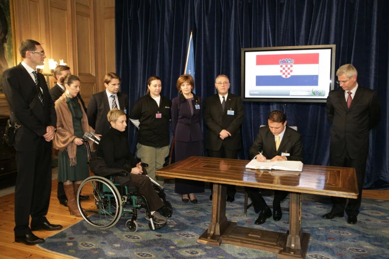 a large group of people are gathered around a man in a wheelchair