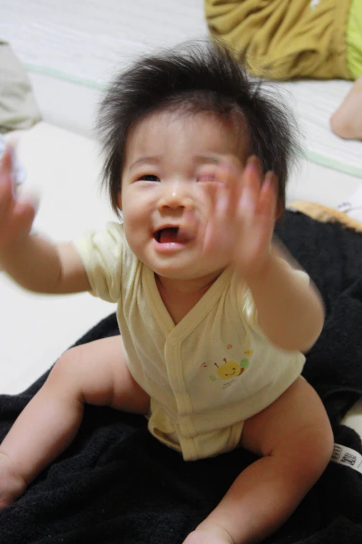 the young child is sitting on the bed waving