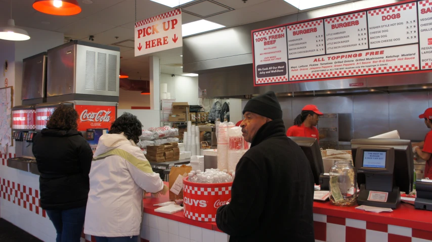 several people standing at the counter of a fast food place
