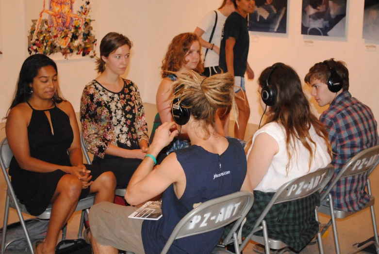 a group of women sitting in chairs with one listening to her
