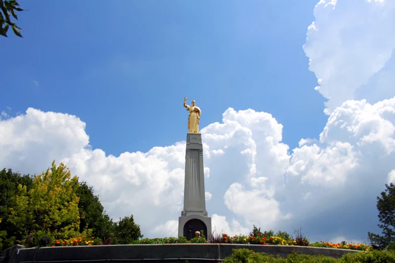 statue with arms up on the side in front of clouds