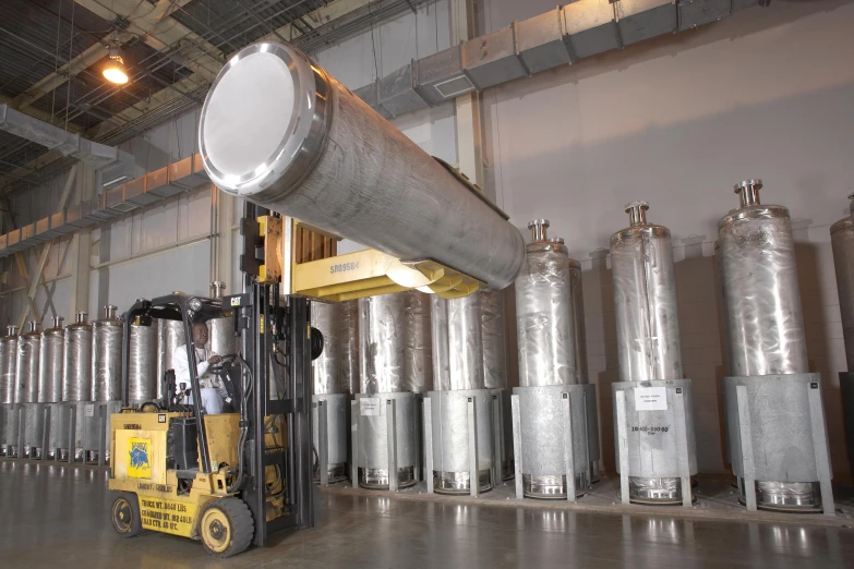 a forklift drives through a large metal barrel filled with fluid