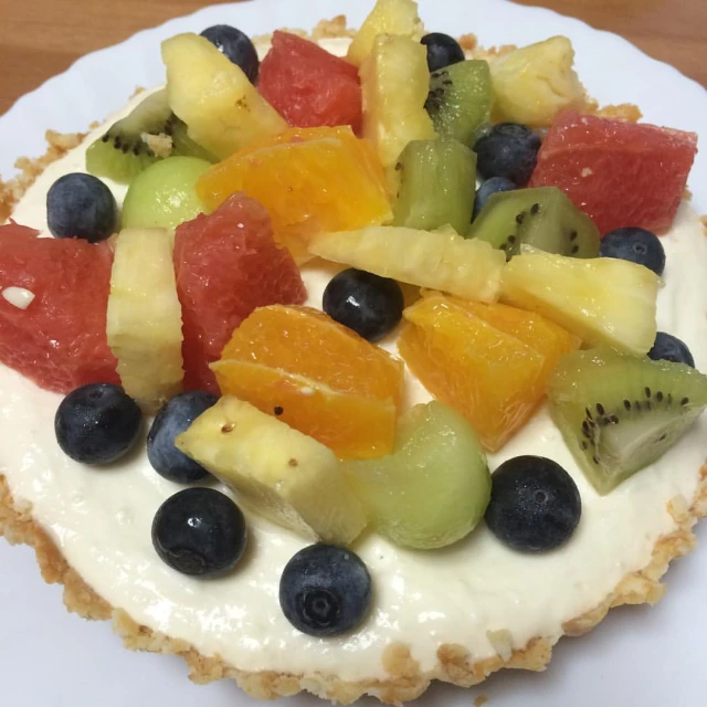 a white plate with a white frosting pie topped with fruit