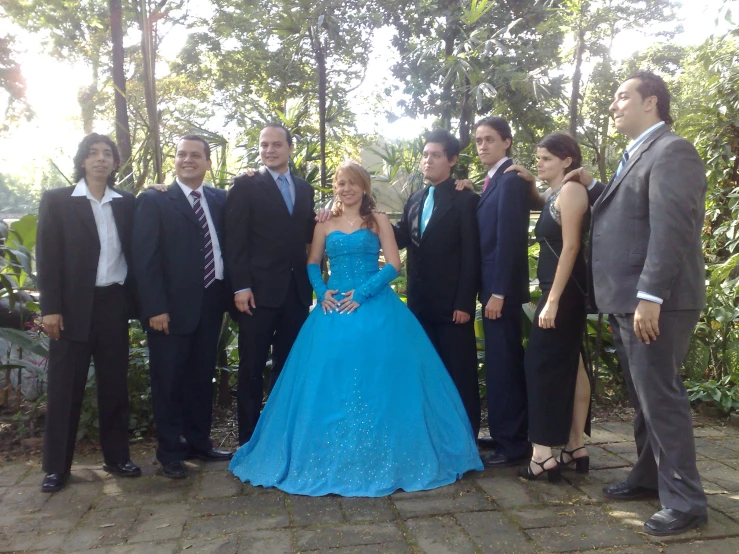 a group of people posing for a po with one woman in a blue gown