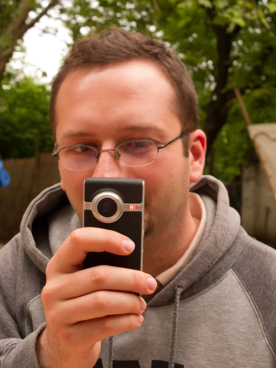 a man in hoodie taking a selfie with his cell phone