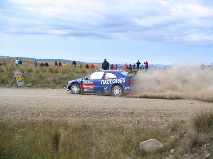 a car on a dirt road near a bunch of people