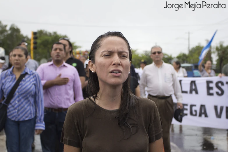 a woman standing in the rain with other people in the background