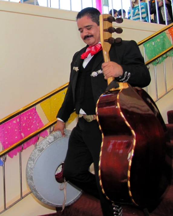 man in tuxedo and tie standing in front of guitar