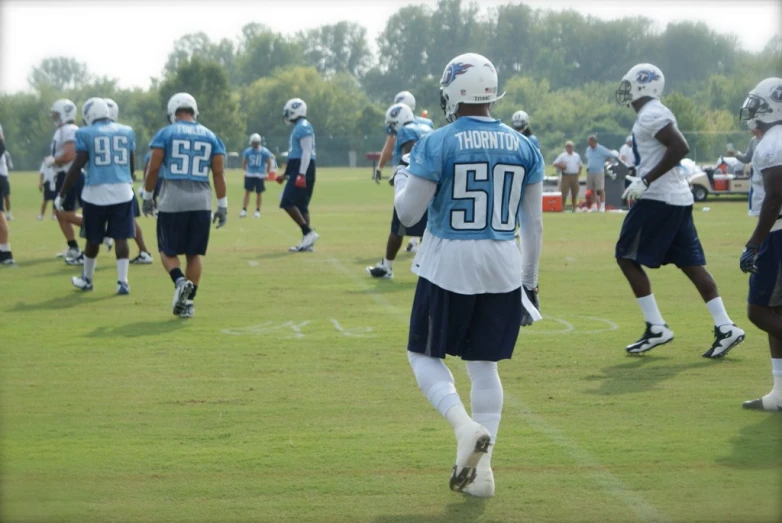 a football player is warming up while other players are practicing