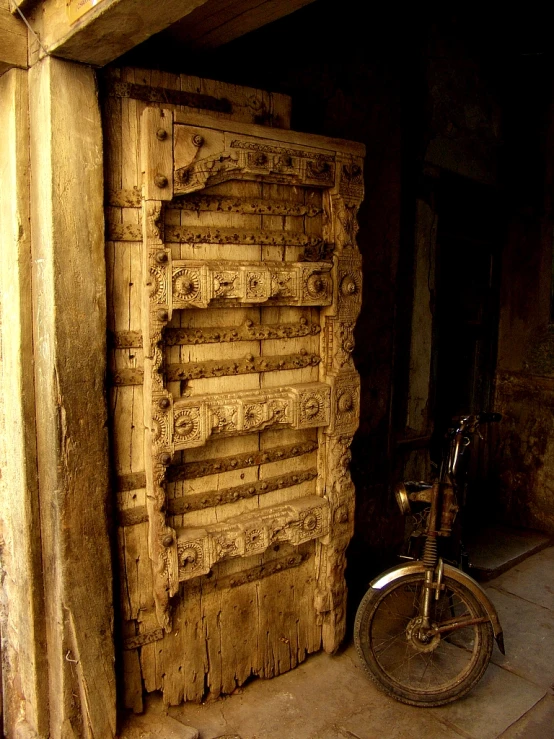 an old bicycle sitting by a wooden door