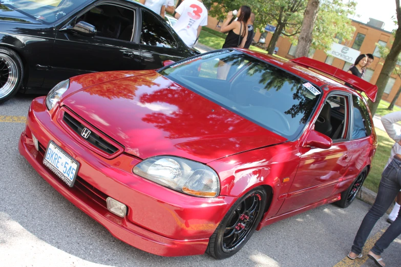 two red and black sedans on display in front of people