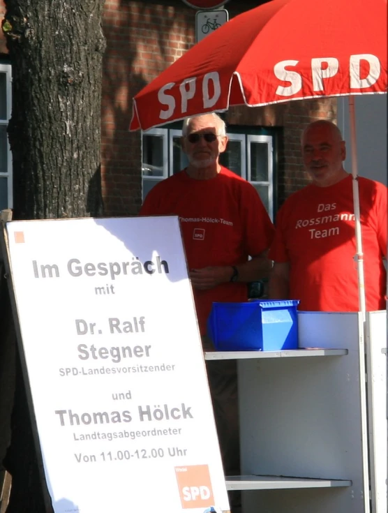 some men under an umbrella and some signs