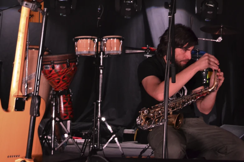 a man that is sitting down playing a saxophone