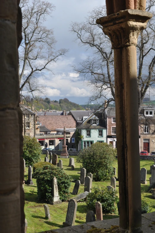 a cemetery with graves, trees and buildings