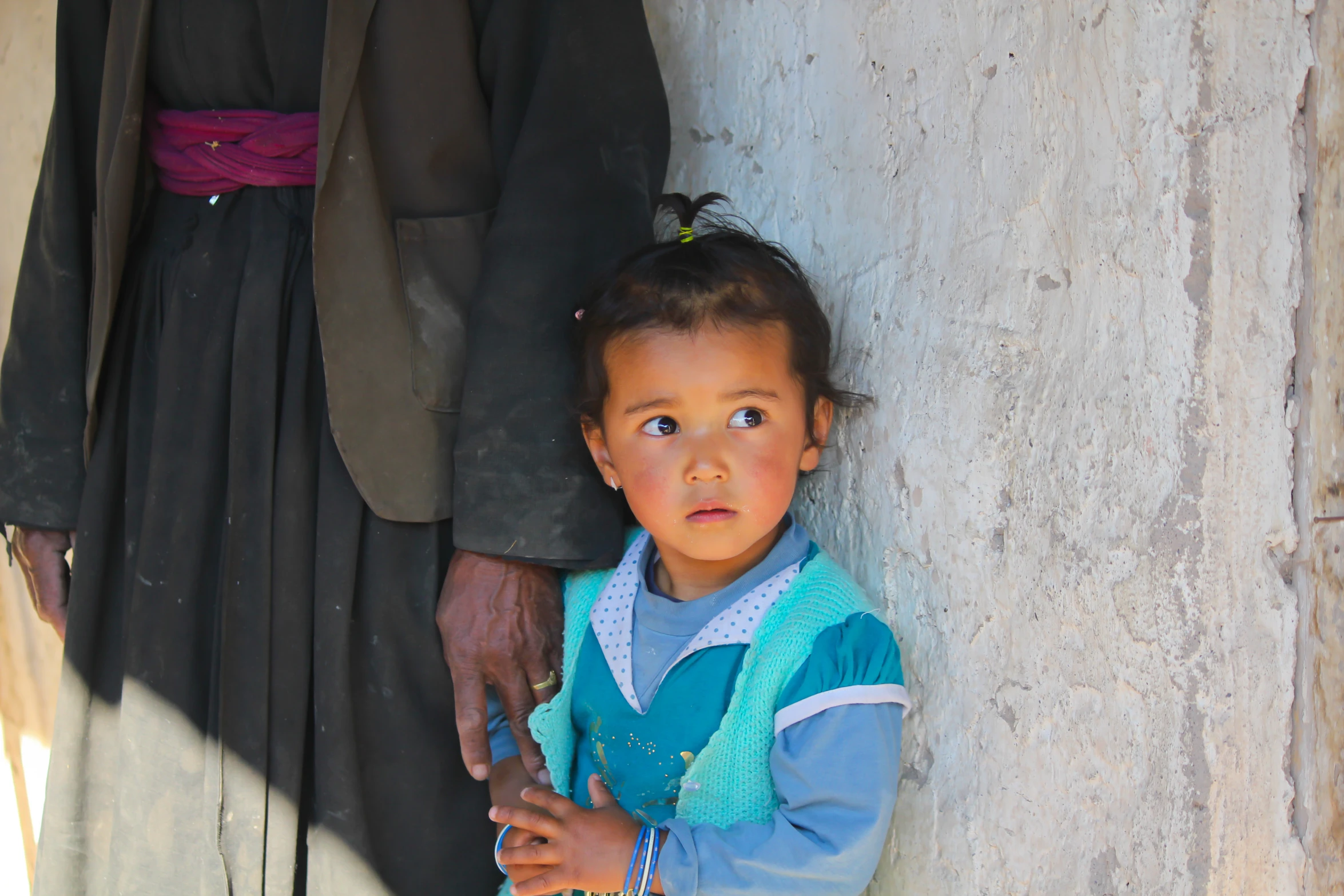 a child standing next to a man holding a cell phone