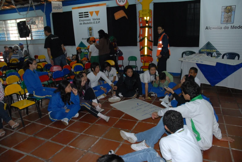 a crowd of young people sitting on top of a floor