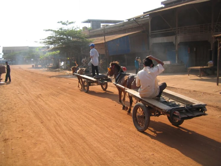 a man riding on the back of a cart pulled by horses