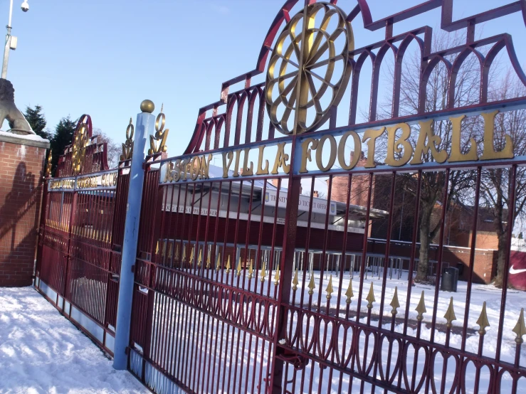 an ornate red metal fence with flags on the top